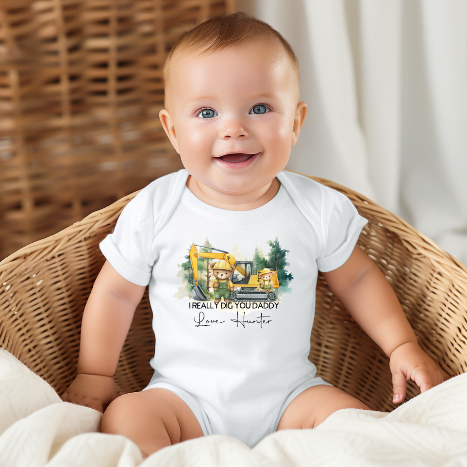 Baby wearing a personalised I Really Dig You Daddy onesie with digger truck print and custom name, perfect for Father’s Day.
