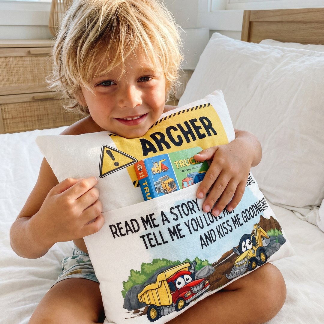 Personalised construction pocket book cushion with trucks and excavators, featuring a built-in book pocket and child’s name.