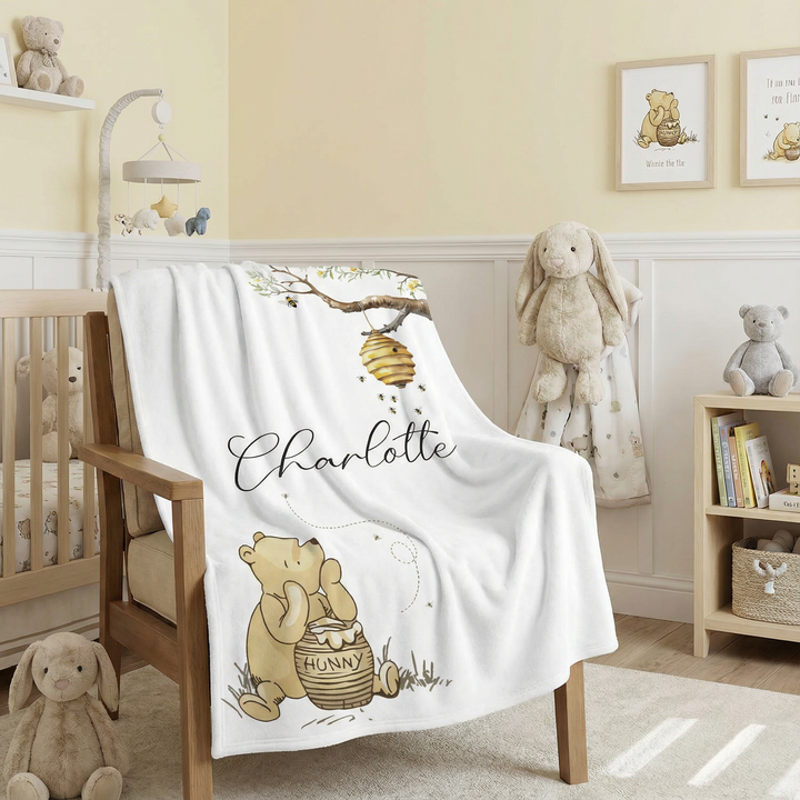 Nursery room with a crib, teddy bears, and a blanket featuring a bear and honey pot design.